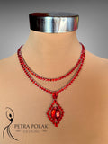 Red beaded necklace with a pendant on a mannequin, branded 'Petra Polak Designs'.