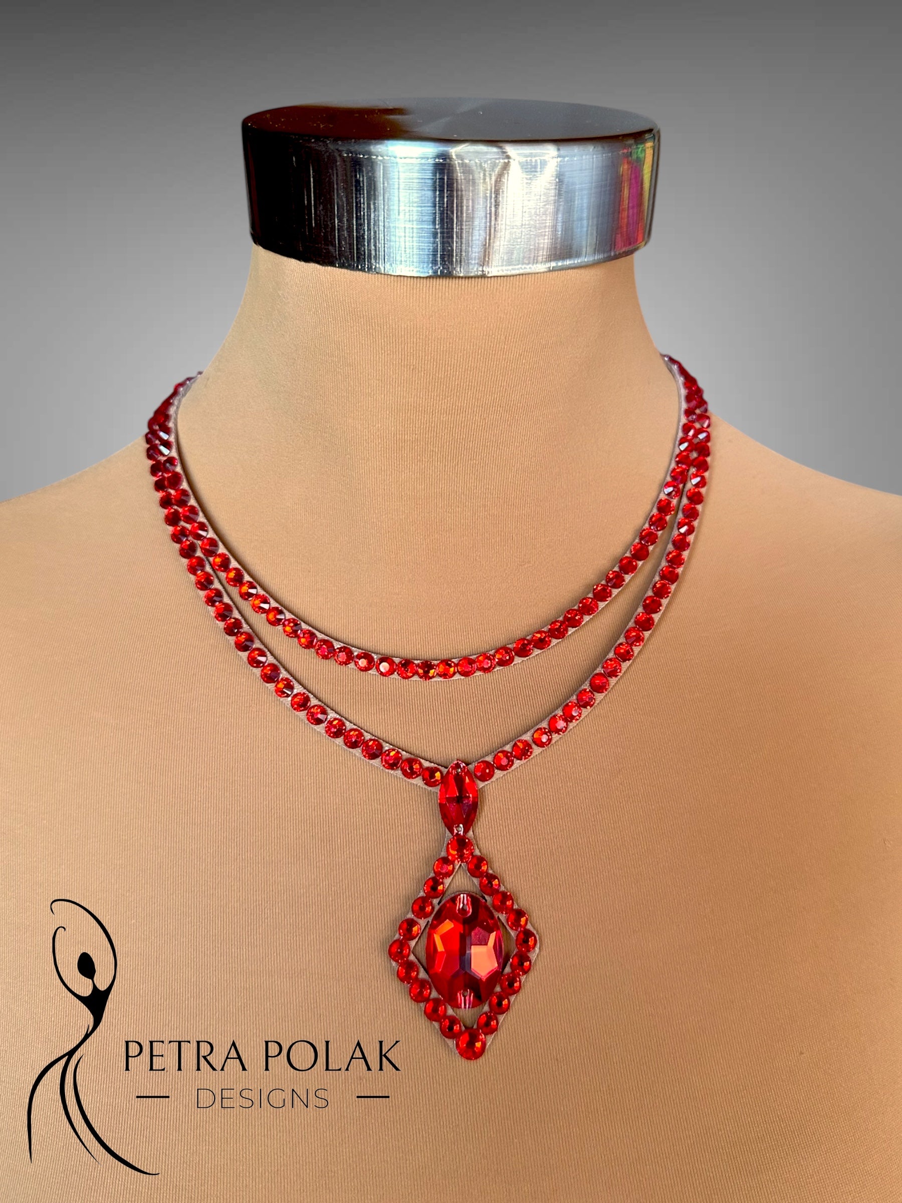 Red beaded necklace with a pendant on a mannequin, branded 'Petra Polak Designs'.