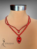 Red beaded necklace on a mannequin with 'Petra Polak Designs' branding.