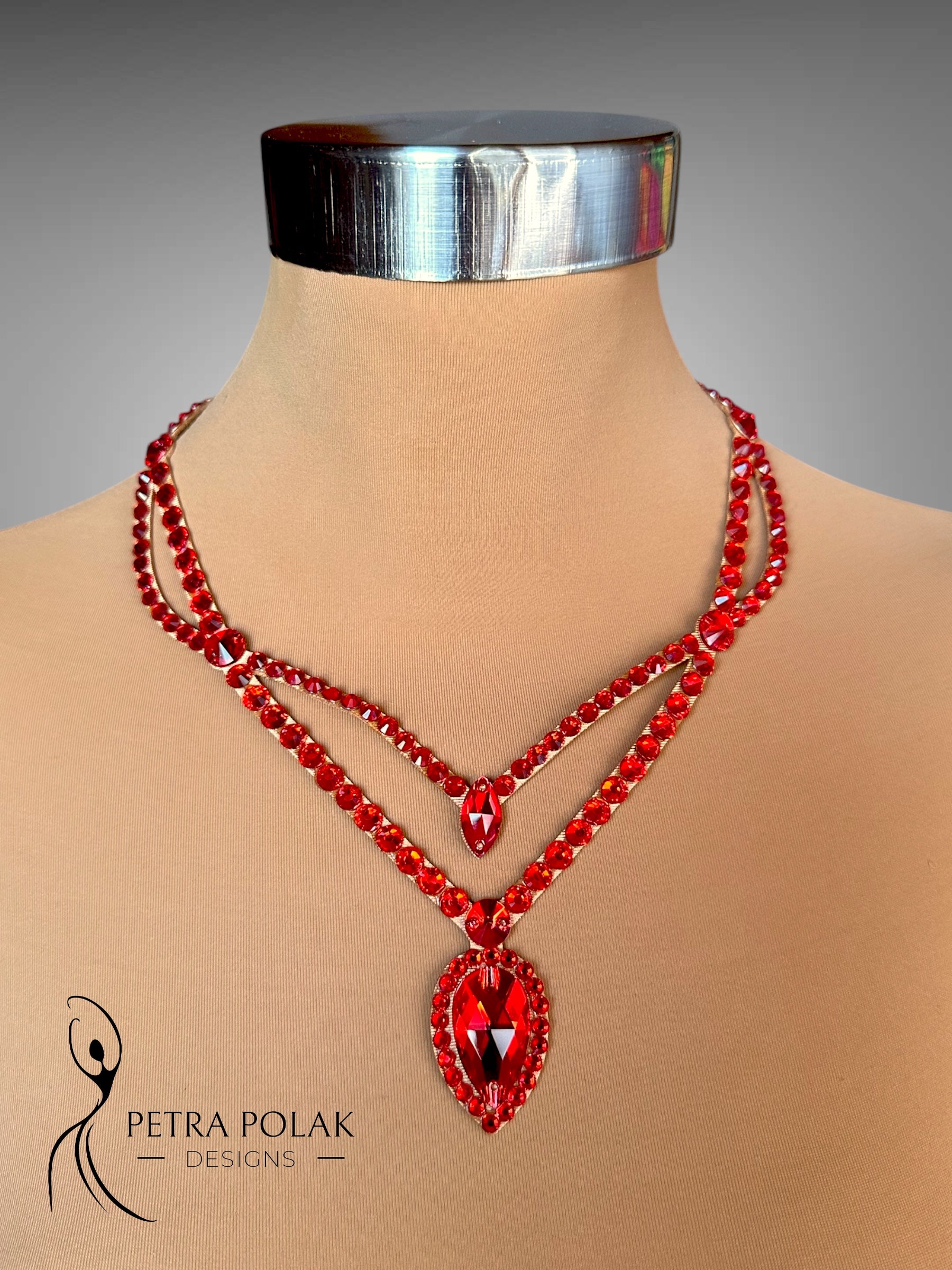 Red beaded necklace on a mannequin with 'Petra Polak Designs' branding.