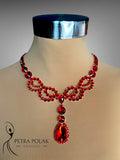 Red beaded necklace on a mannequin with 'Petra Polak Designs' branding.