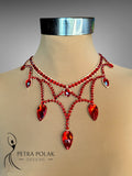Red beaded necklace on a mannequin with 'Petra Polak Designs' branding.