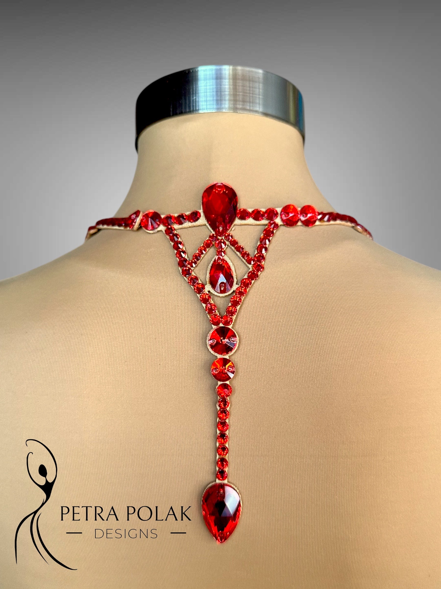 Red gemstone necklace on a mannequin with 'Petra Polak Designs' branding.