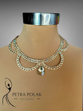 Gold necklace on a mannequin with 'Petra Polak Designs' branding.