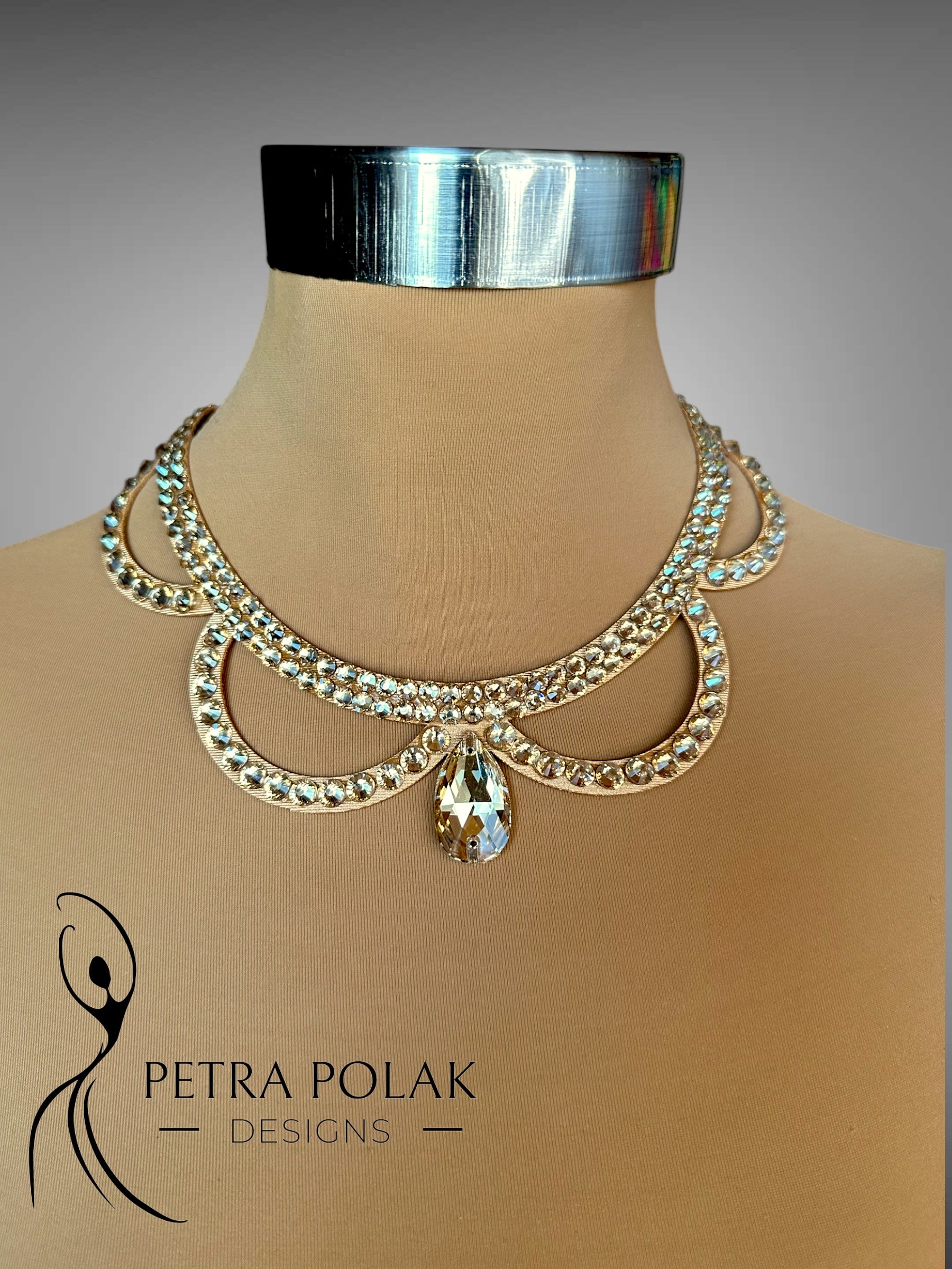 Gold necklace on a mannequin with 'Petra Polak Designs' branding.