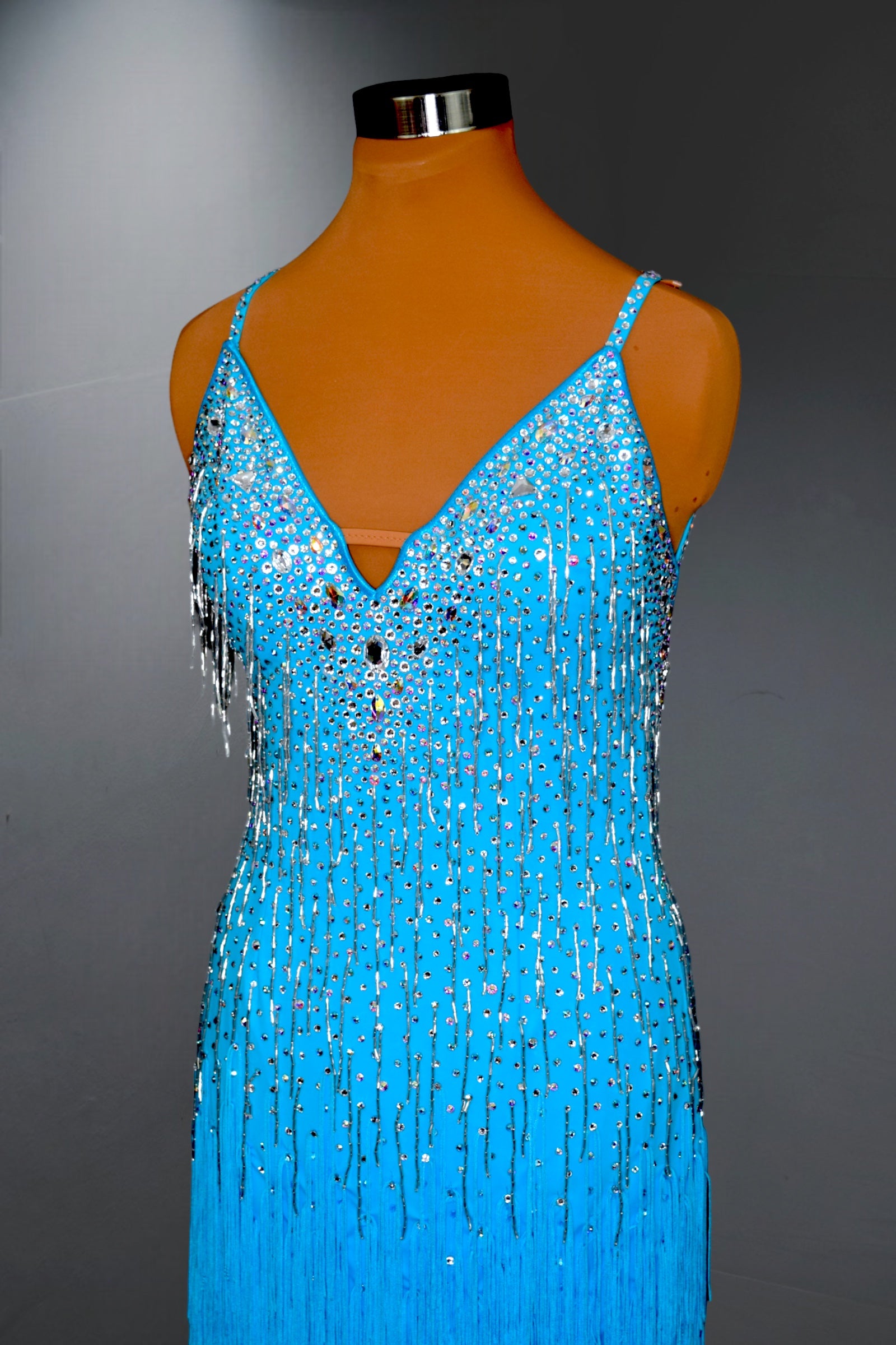 Blue beaded dress on a mannequin against a gray background