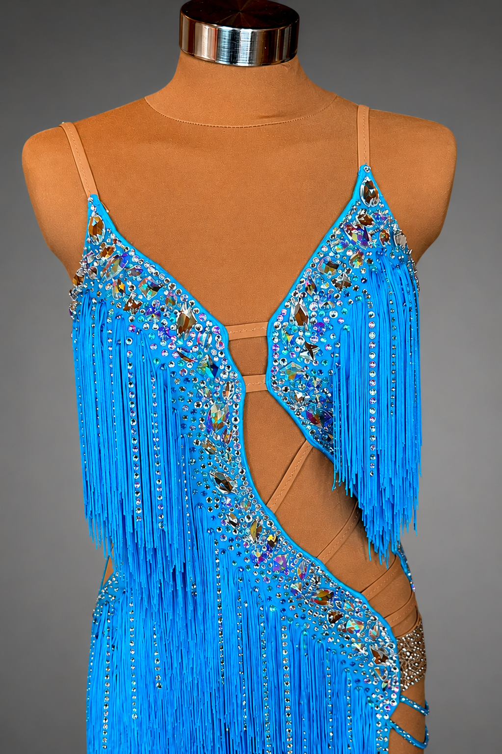 Blue fringe and beaded dress on a mannequin against a gray background