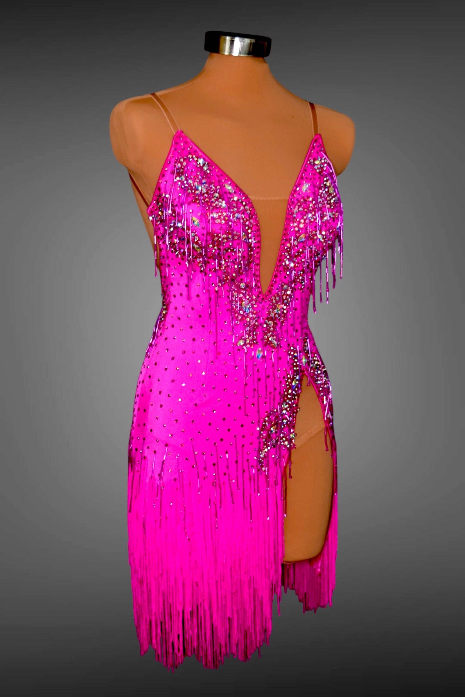Pink dress with fringe and sequins on a mannequin against a gray background