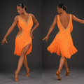Woman in an orange fringe dress posing against a dark background