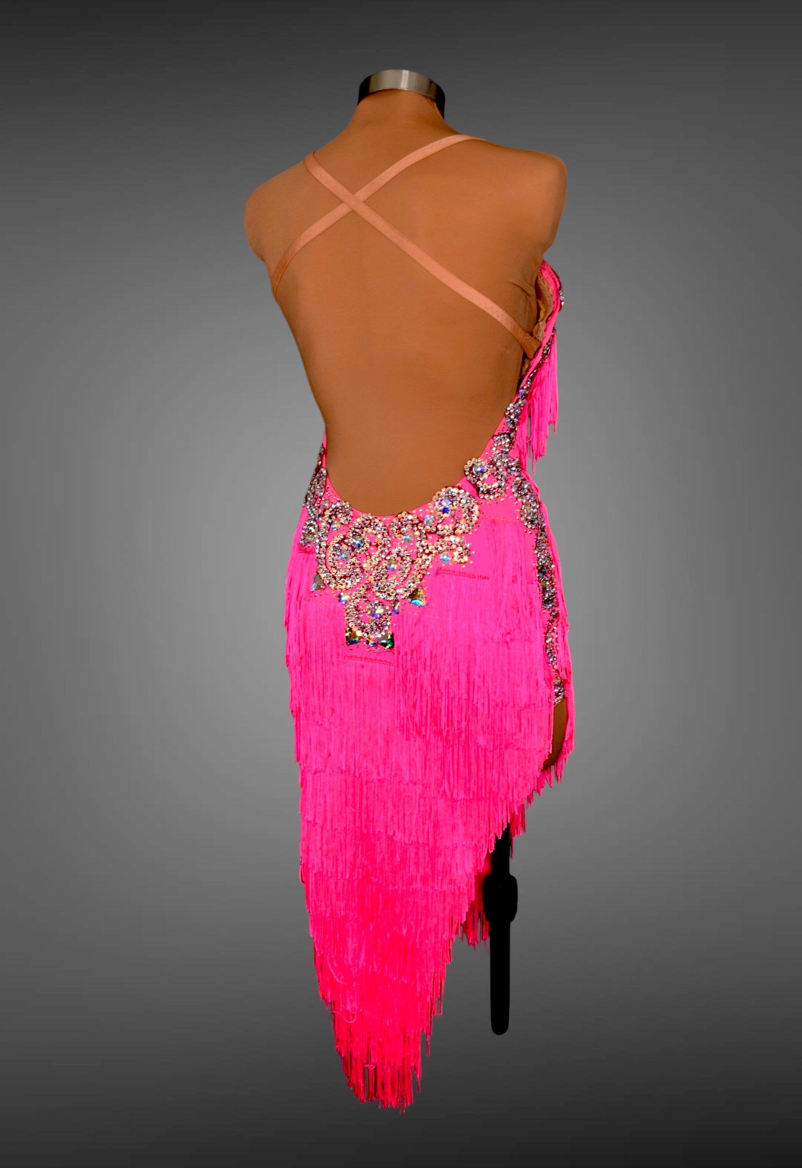 Pink fringe dress with intricate back design on a mannequin against a gray background