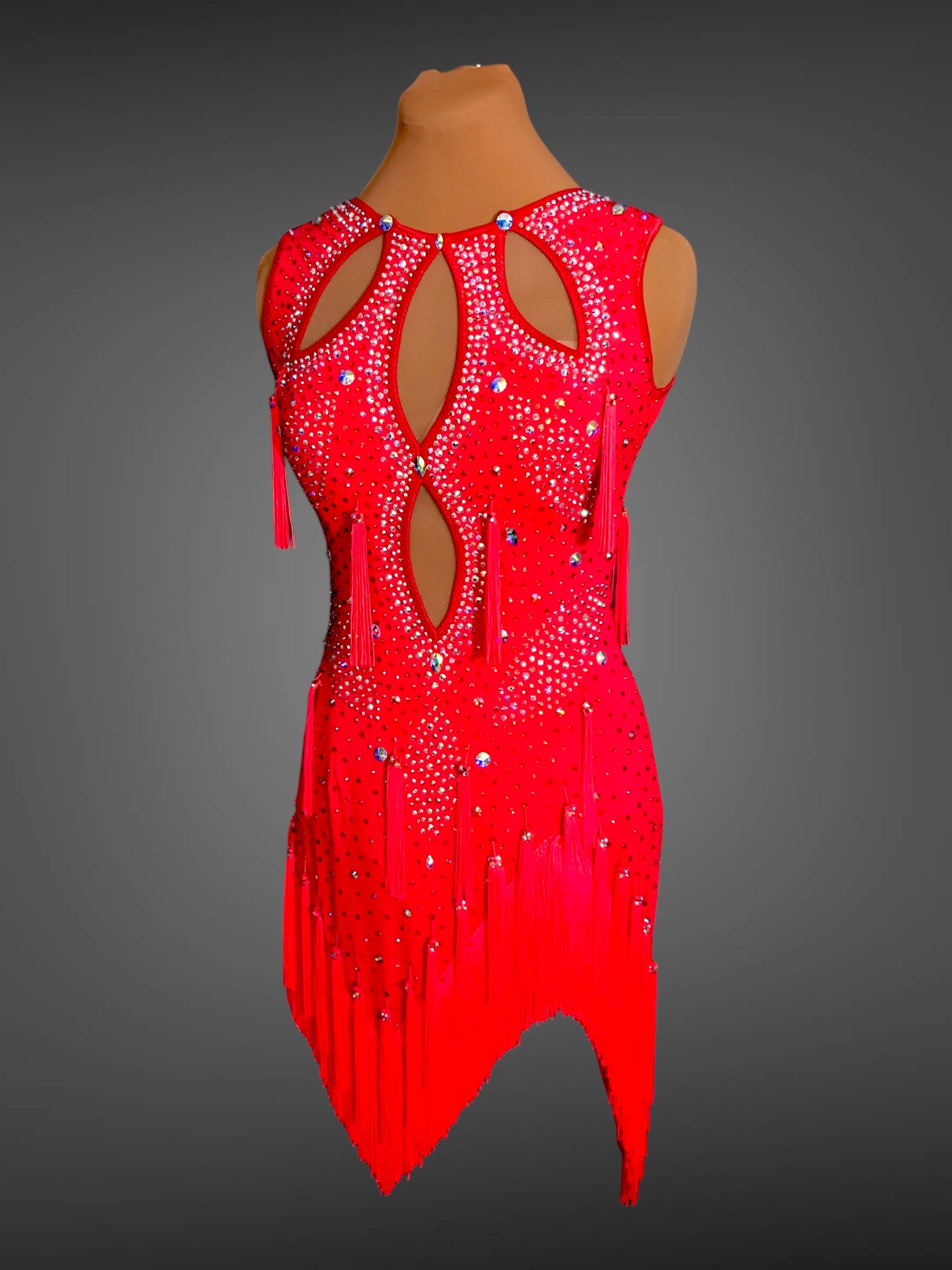 Red dress with fringe and embellishments on a mannequin against a gray background