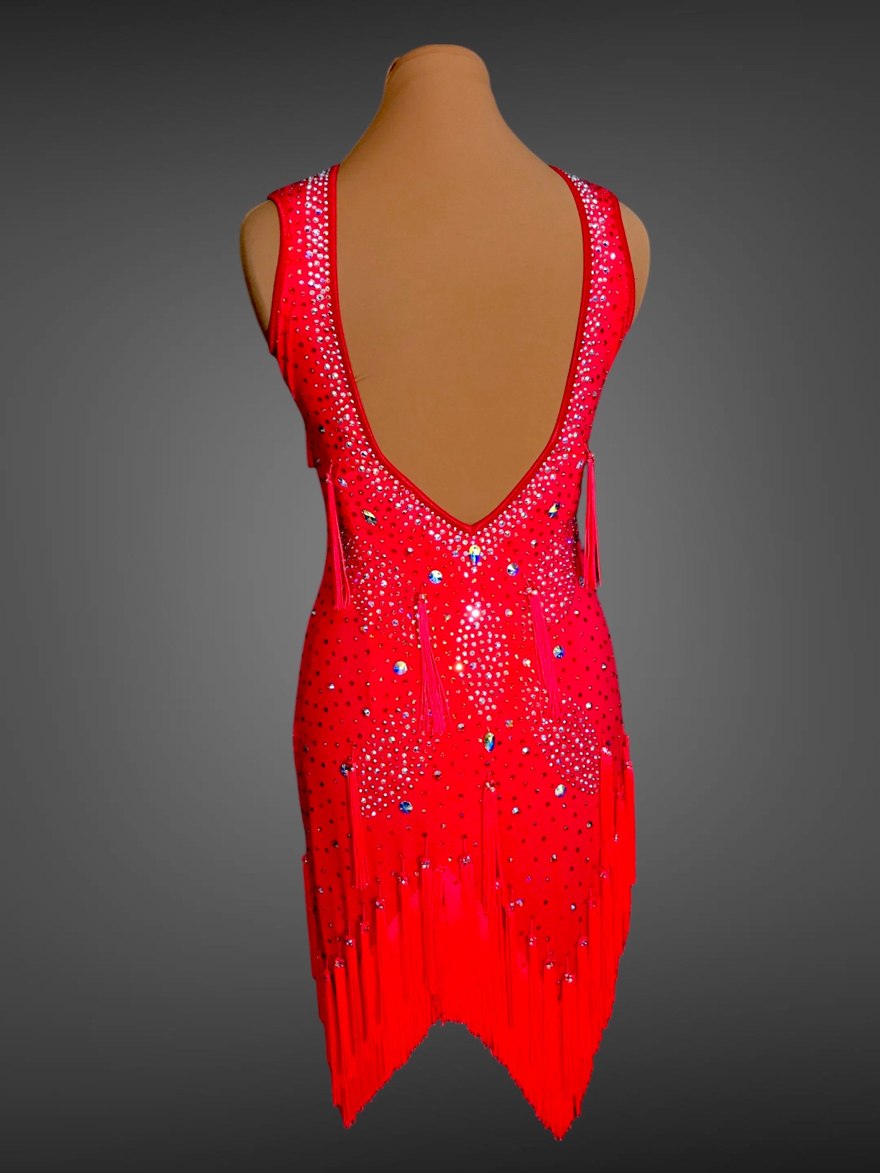 Red dress with fringe and embellishments on a mannequin against a gray background