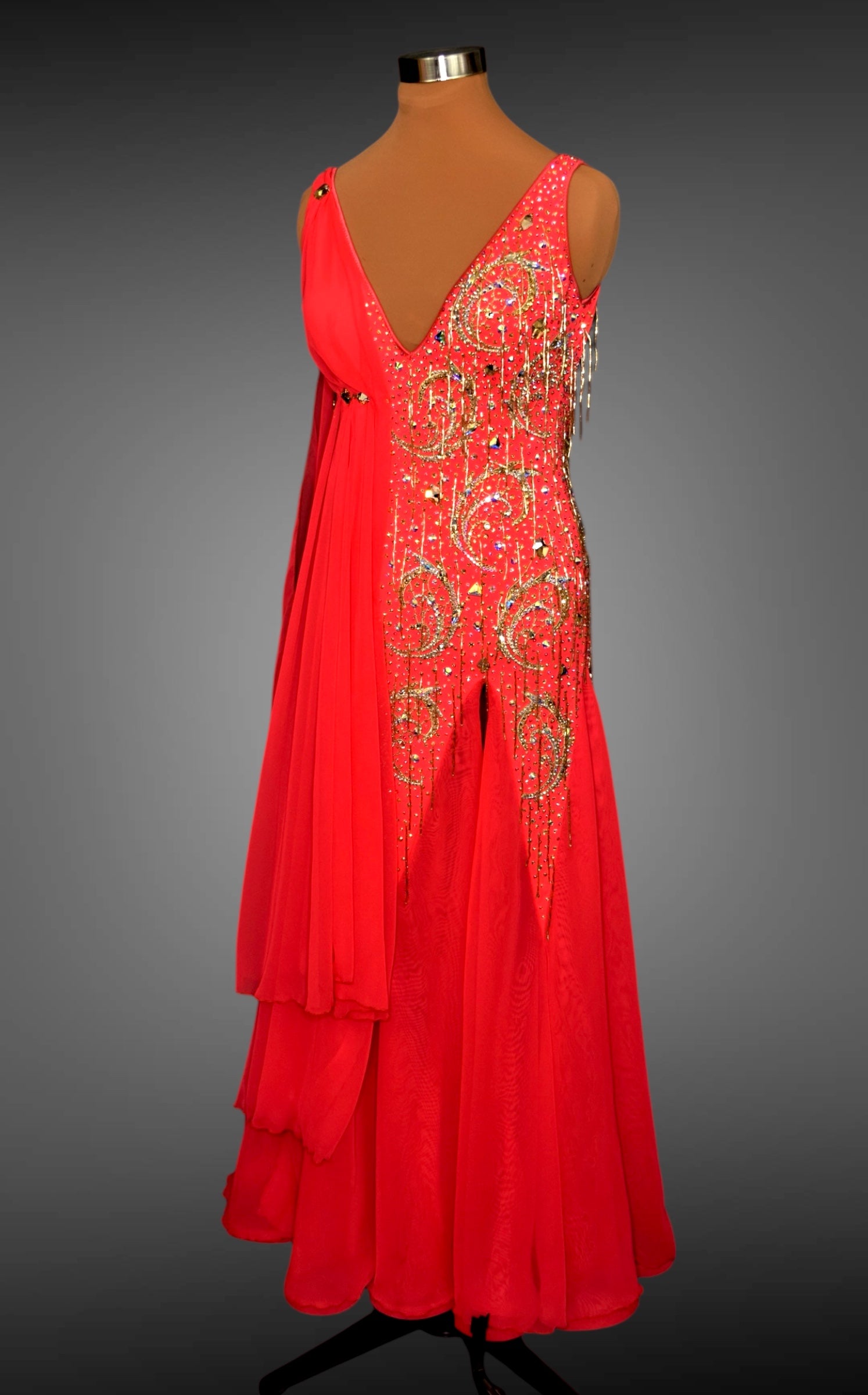 Red evening gown with gold embellishments on a mannequin against a gray background