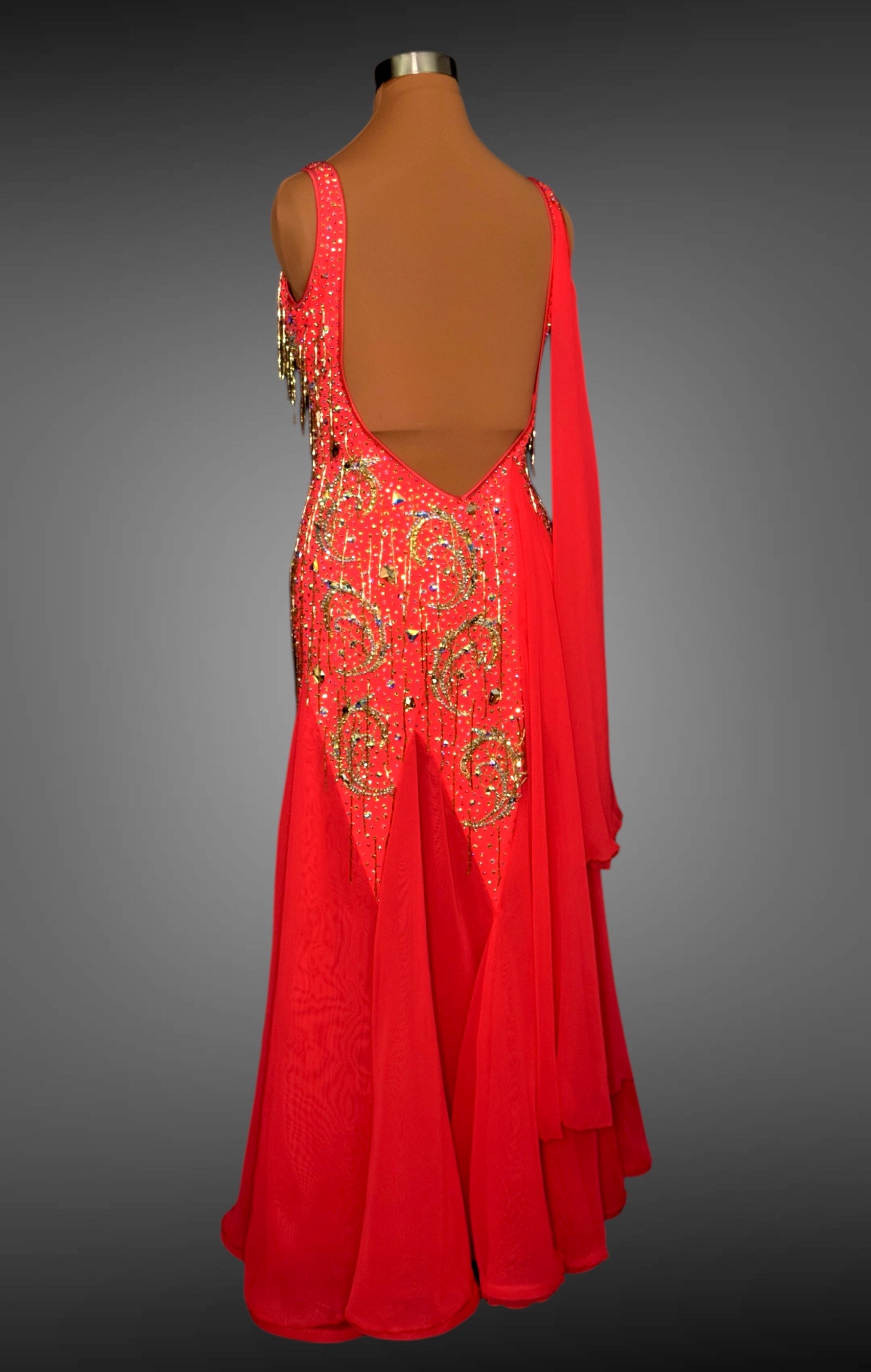 Red evening gown with gold embellishments on a mannequin against a gray background