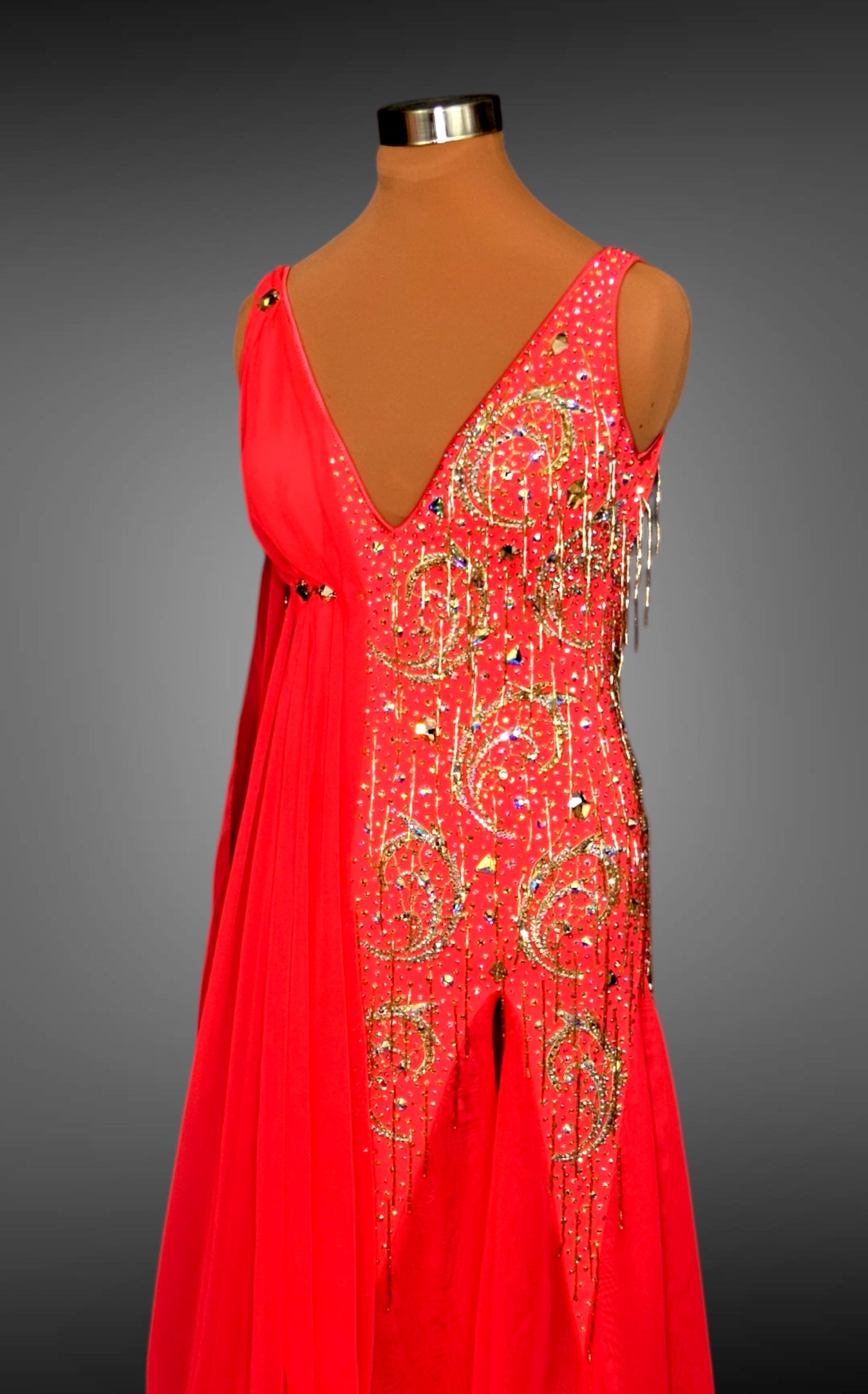 Red evening gown with gold embellishments on a mannequin against a gray background