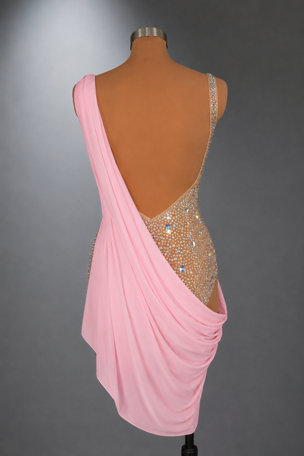 Mannequin wearing a pink draped dress with a beaded back on a gray background