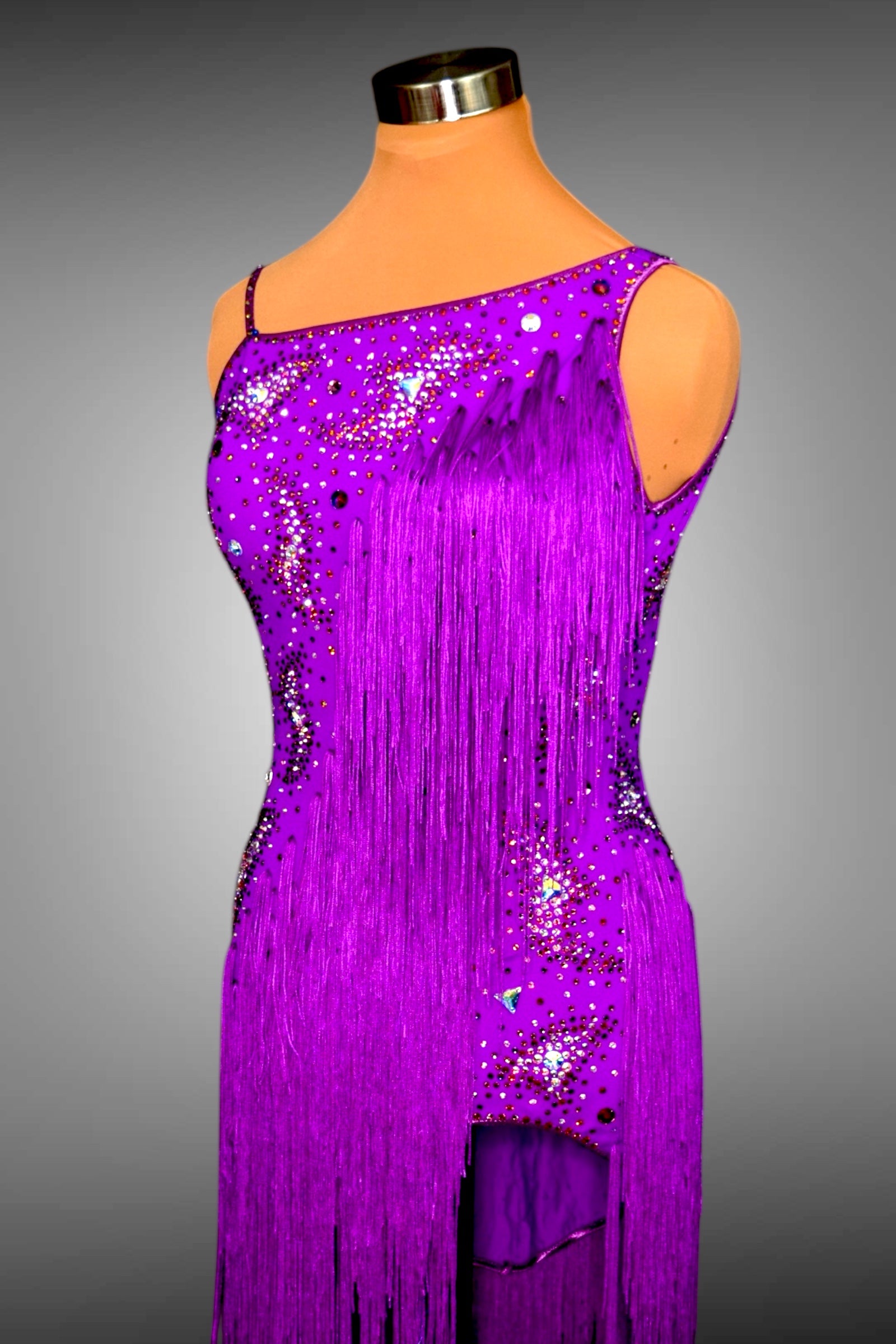 Purple fringe dress on a mannequin against a gray background