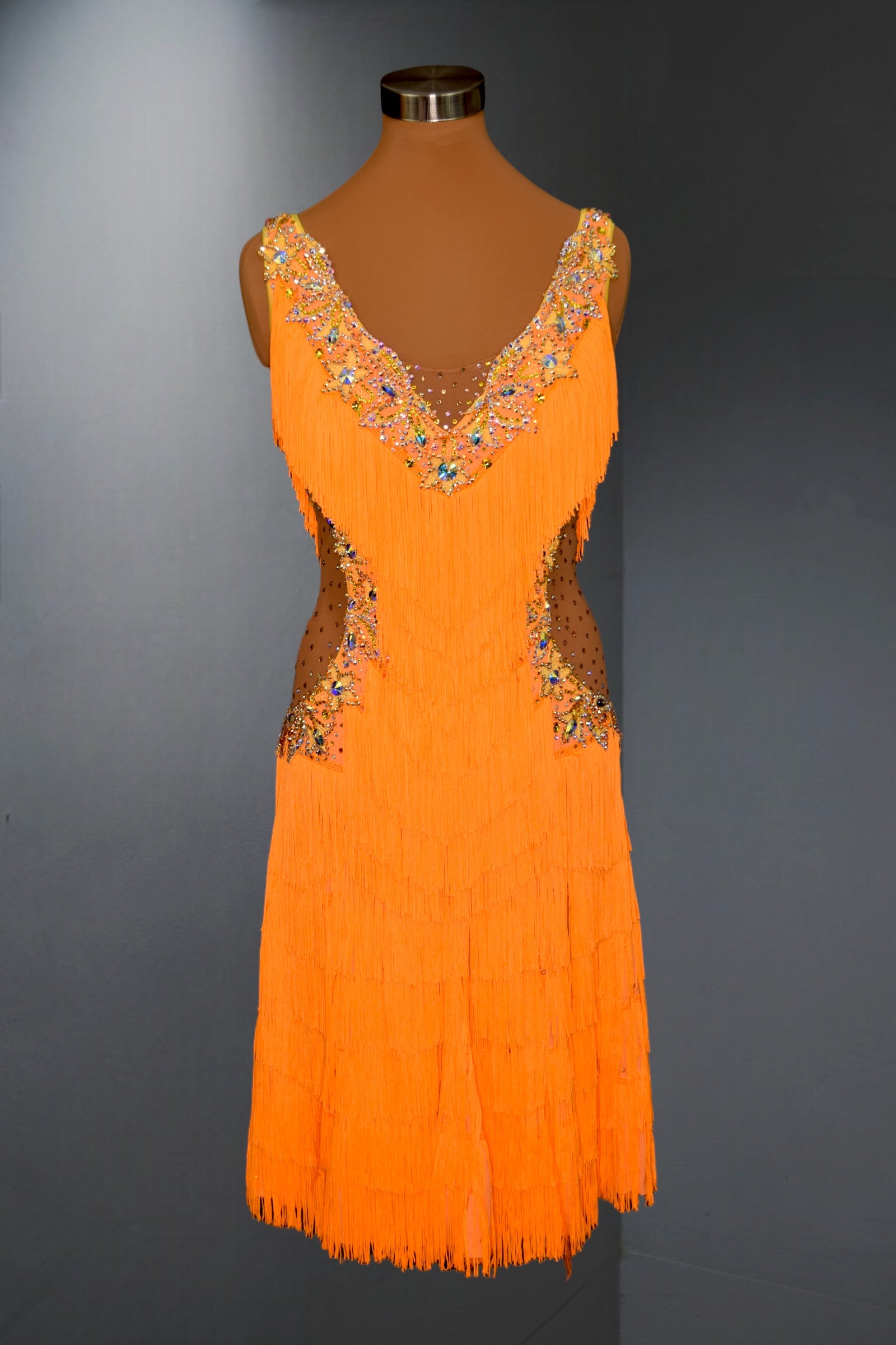 Orange dress with intricate beading on a mannequin against a gray background