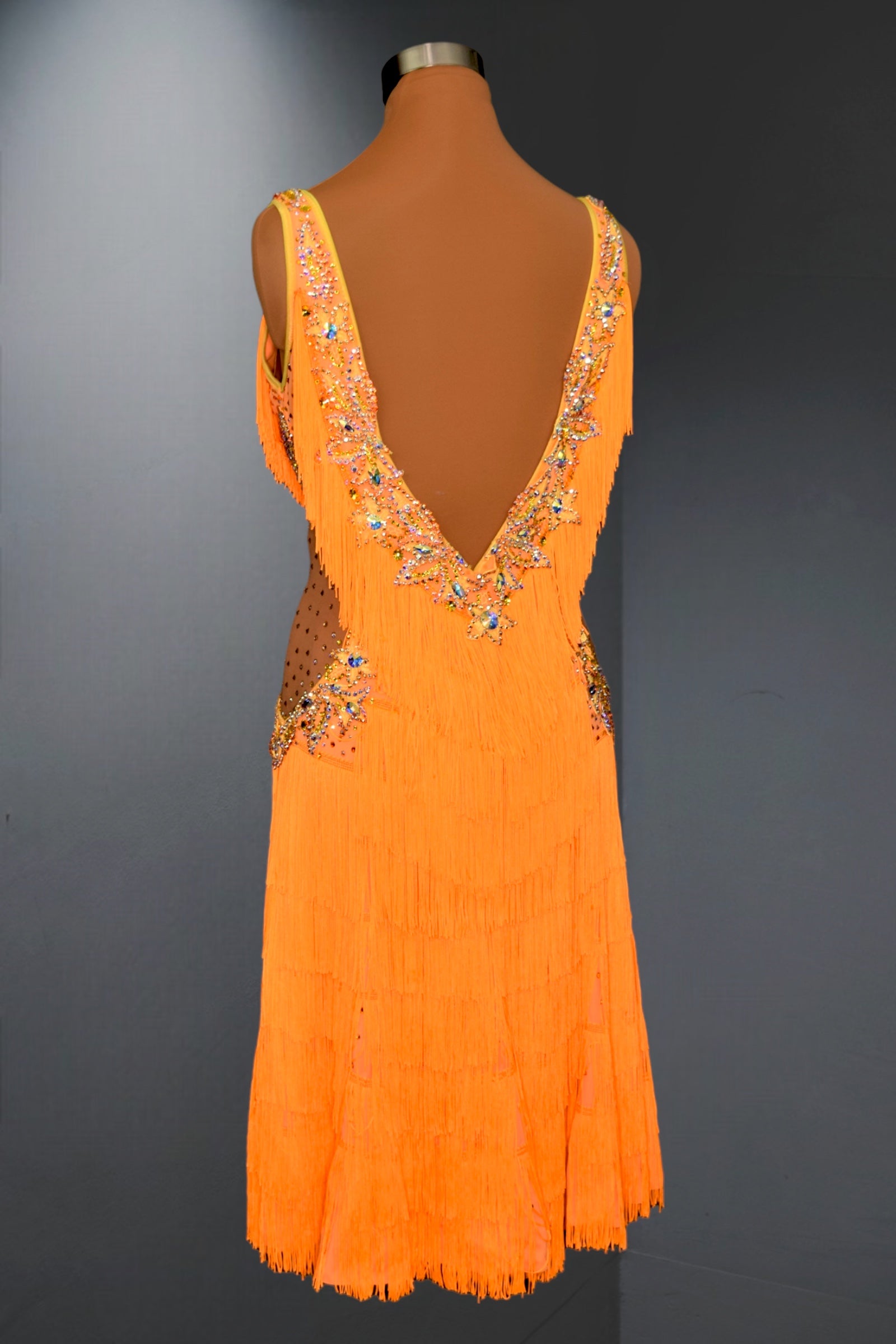 Orange dress with intricate detailing on a mannequin against a dark background