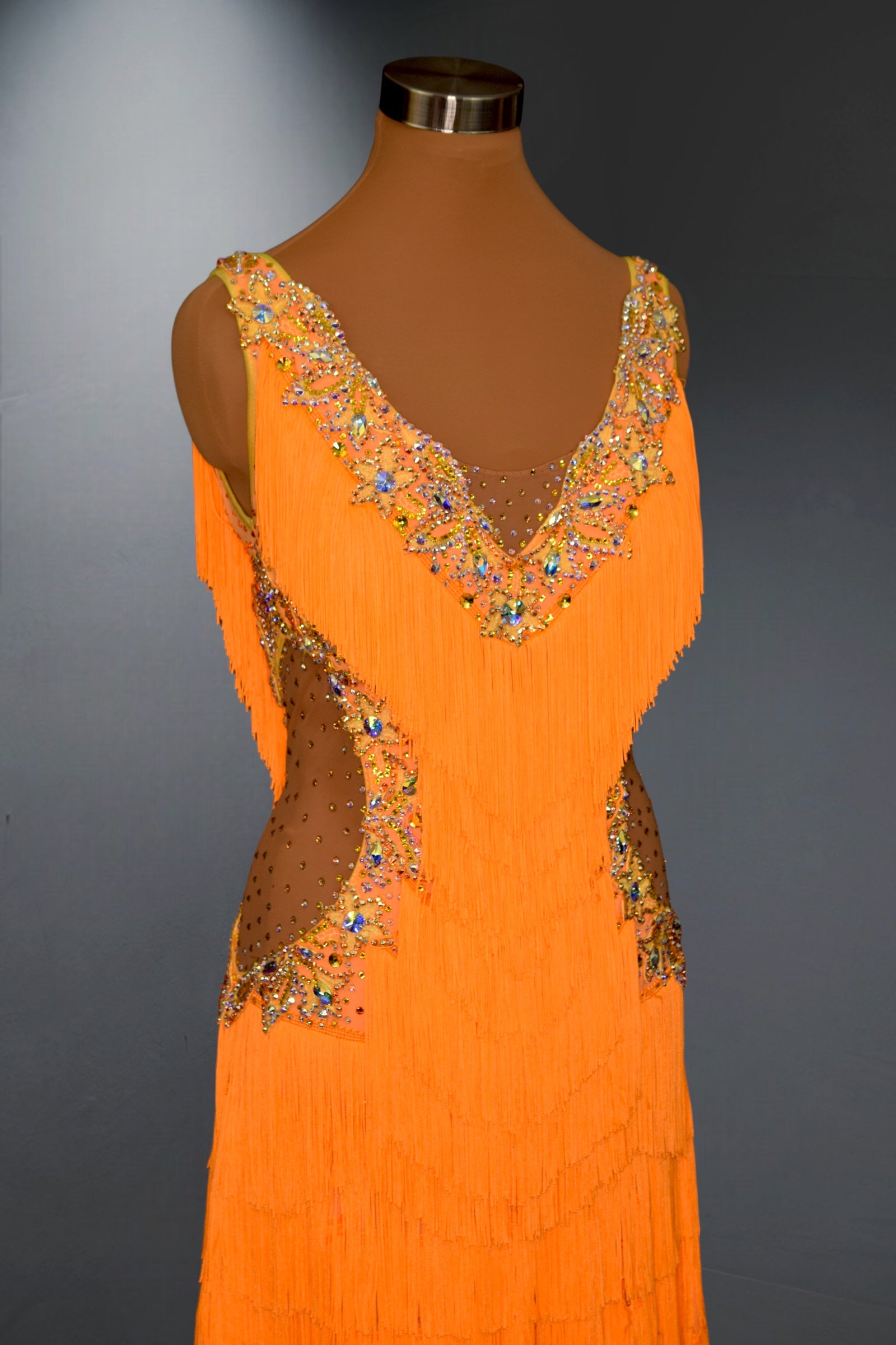 Orange dress with intricate beadwork on a mannequin against a gray background