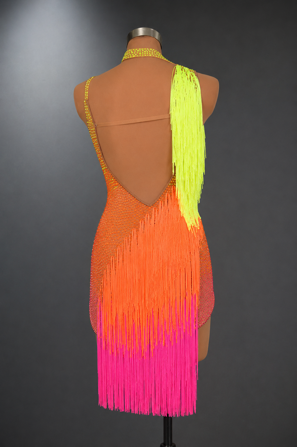 Mannequin wearing a colorful fringe dress with a gradient from orange to pink on a gray background