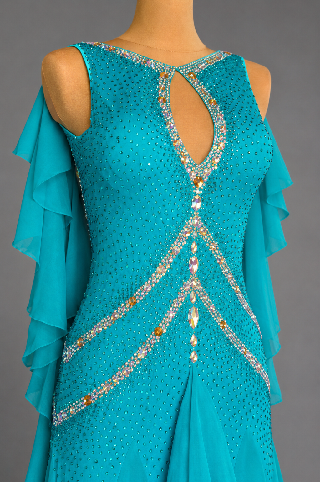 Turquoise dress with intricate beadwork on a mannequin against a gray background
