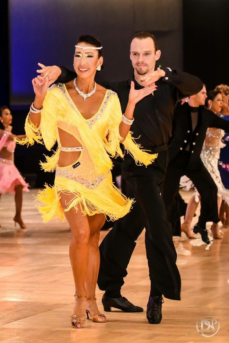 Dancers in formal attire on a dance floor with other dancers in the background