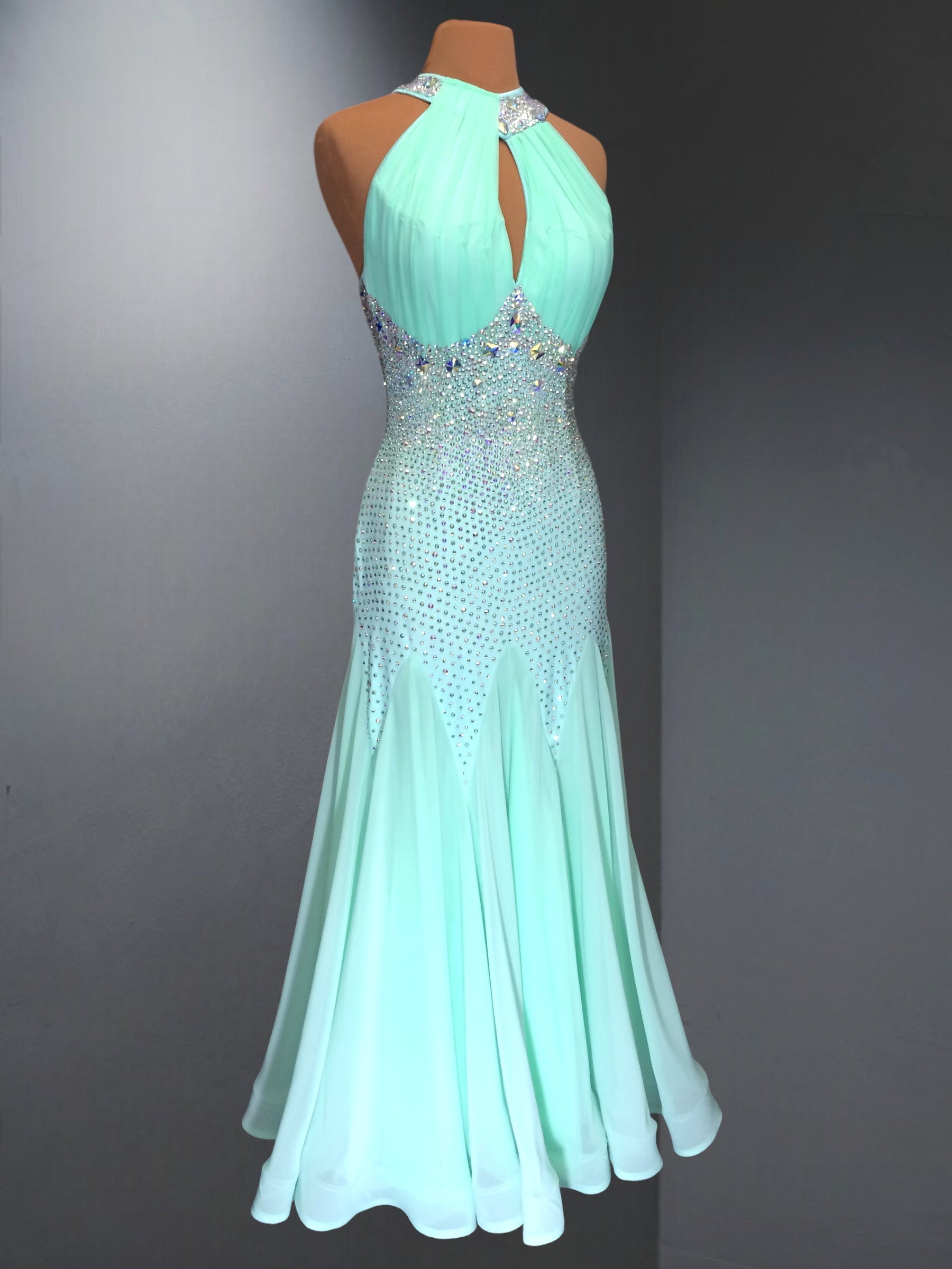 Mint green evening gown with beaded details on a mannequin against a gray background