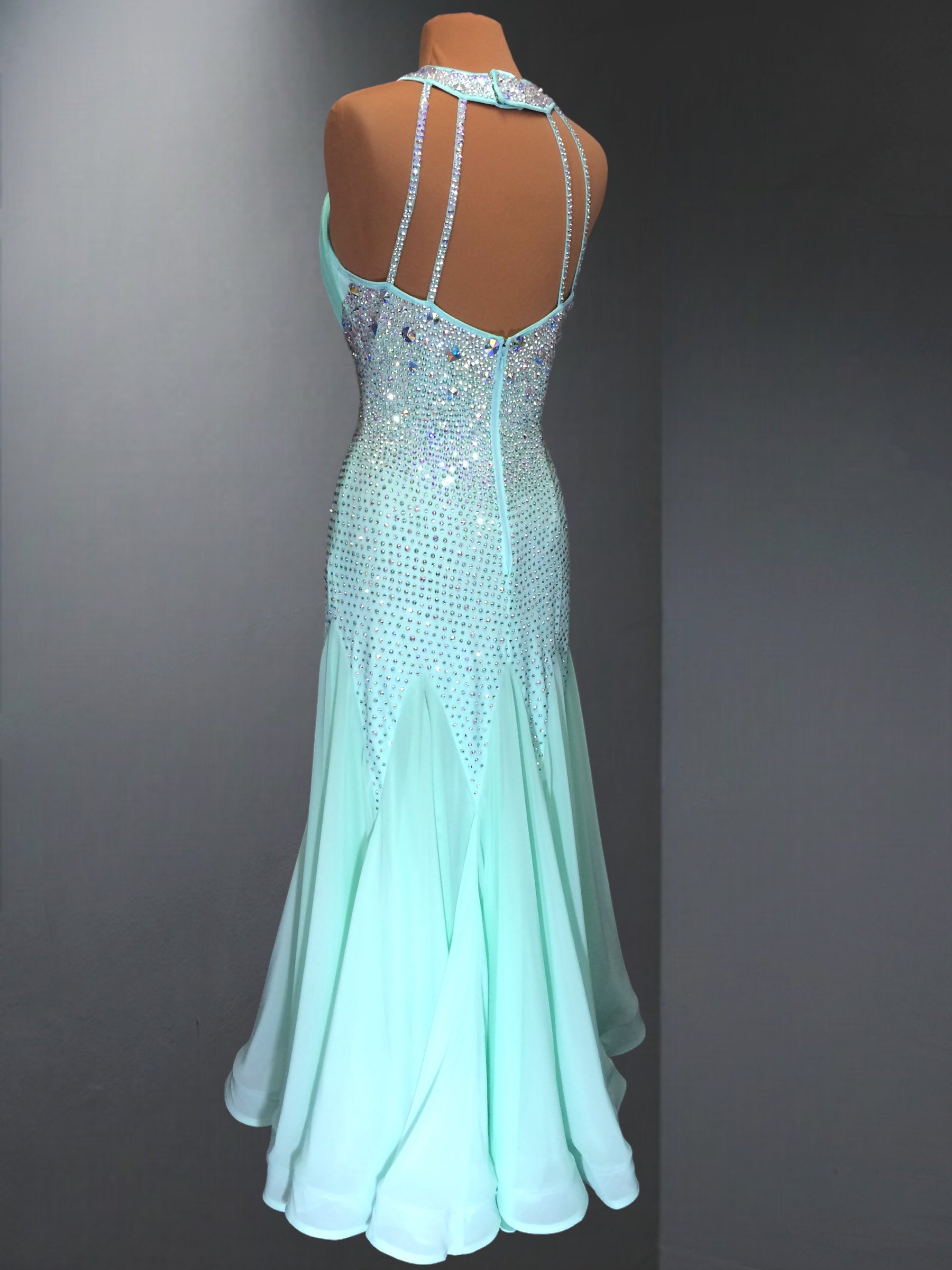 Mint green evening gown with beaded straps on a mannequin against a gray background