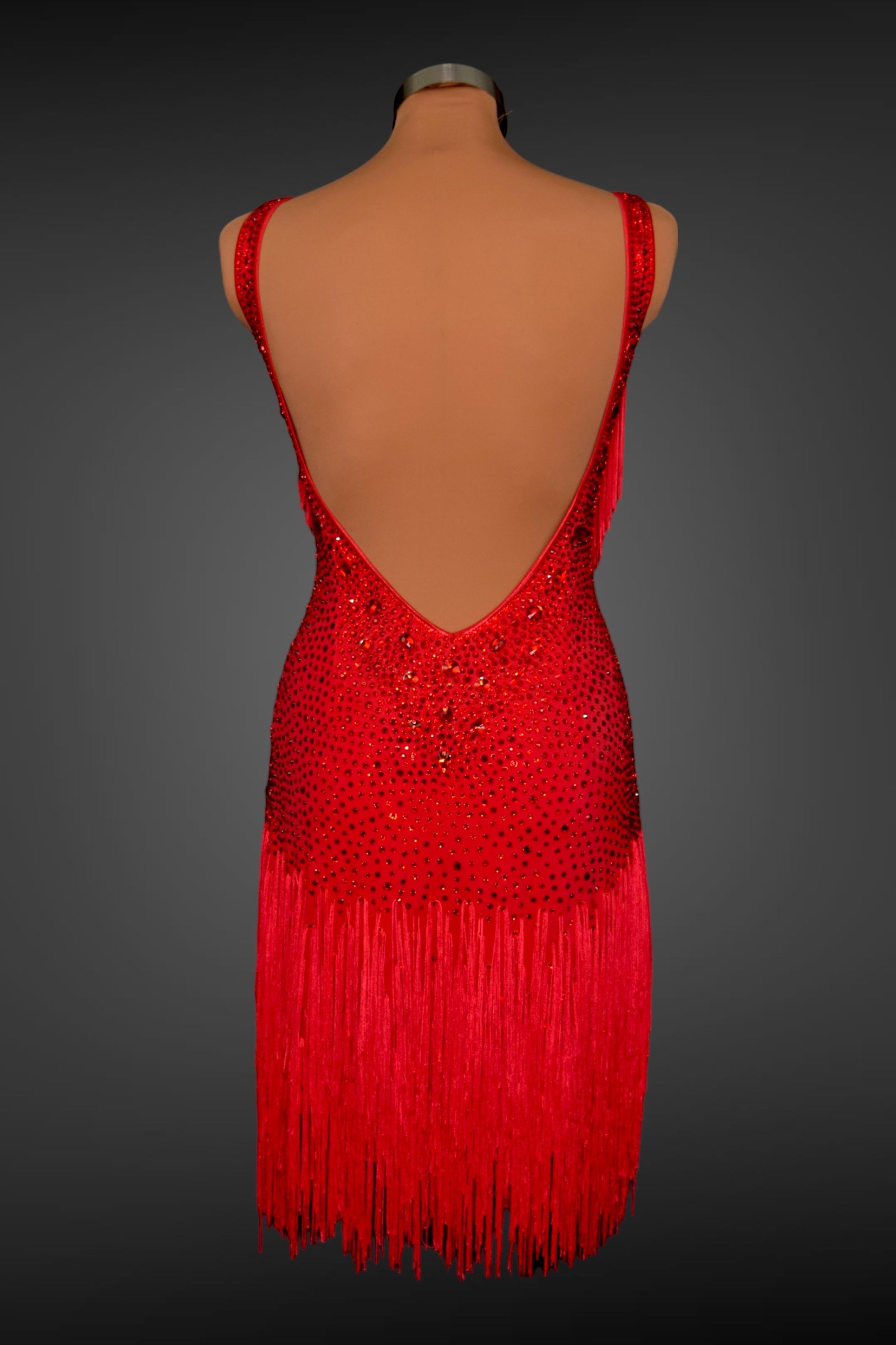 Red dress with fringe and embellishments on a mannequin against a gray background