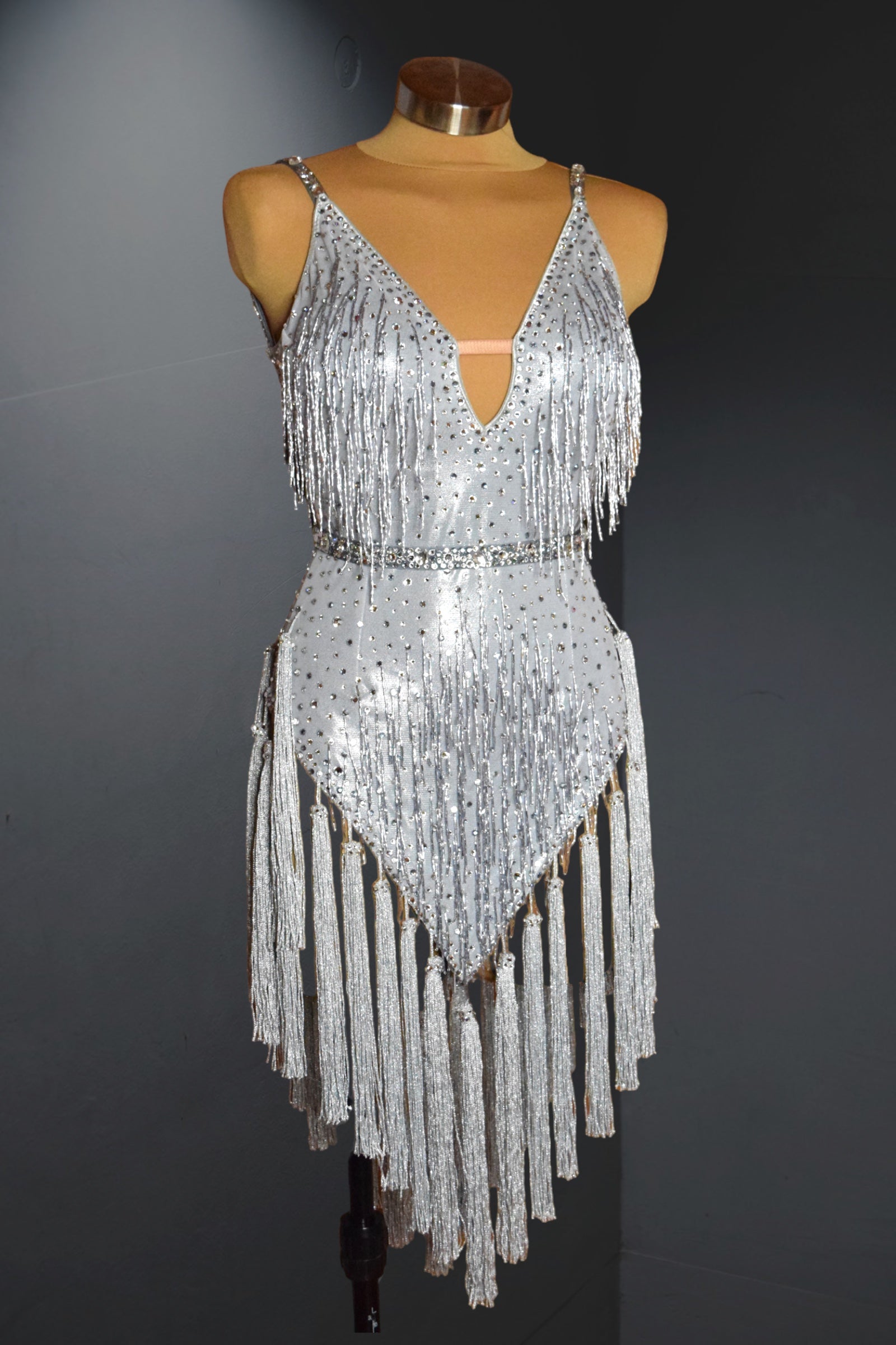 Silver sequin dress with fringe on a mannequin against a dark background