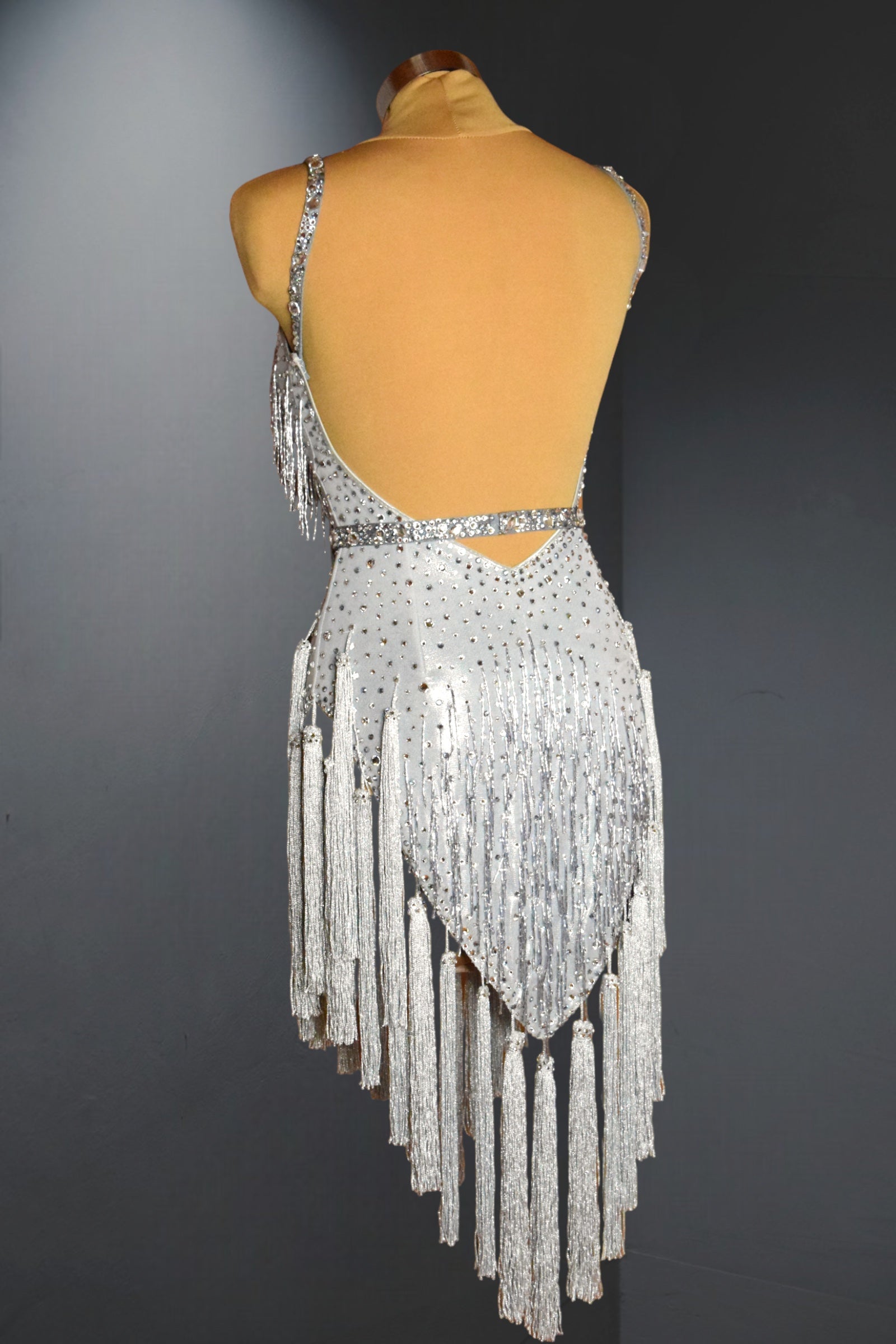 Silver fringe dress on a mannequin against a dark background