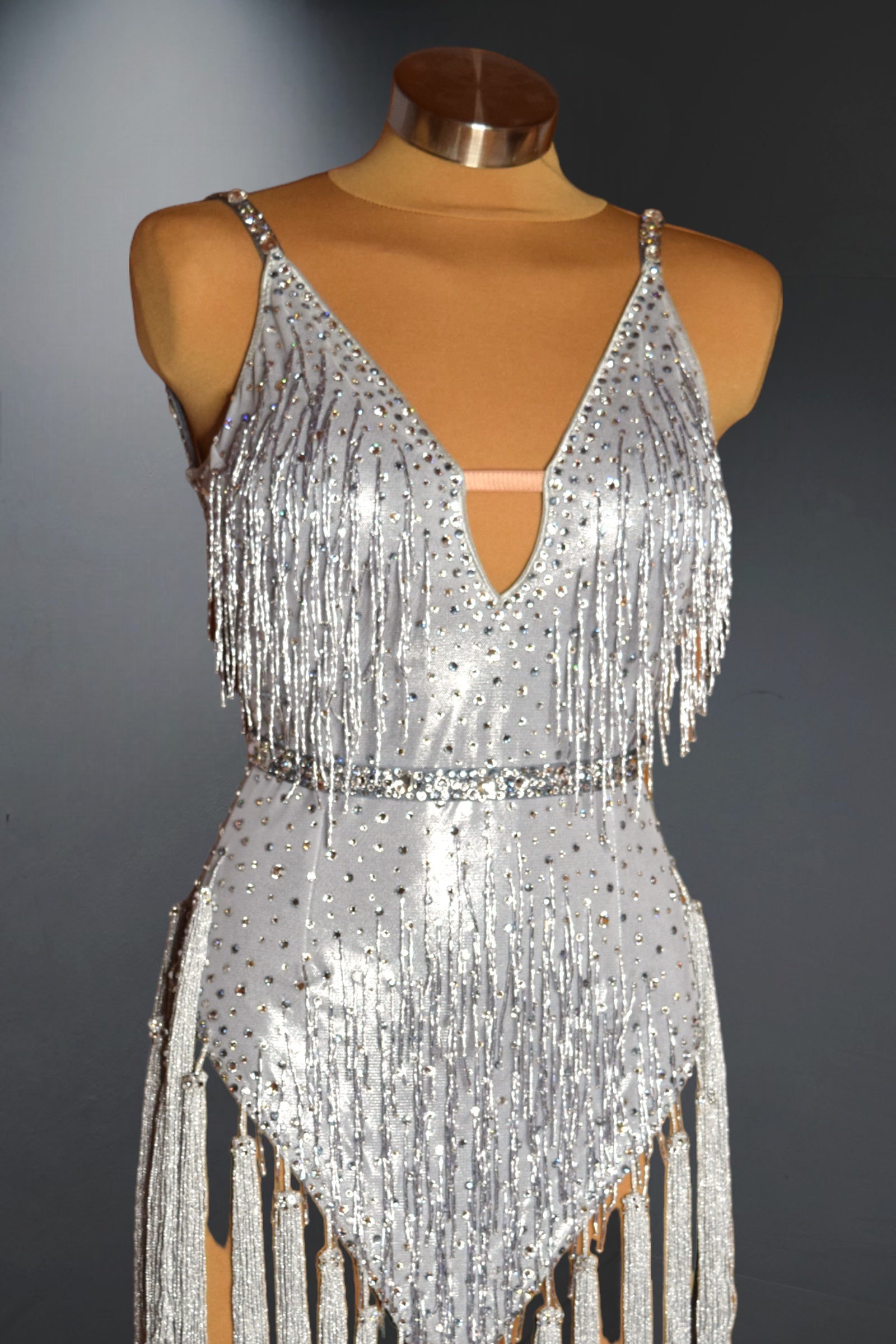 Silver fringe dress on a mannequin against a dark background