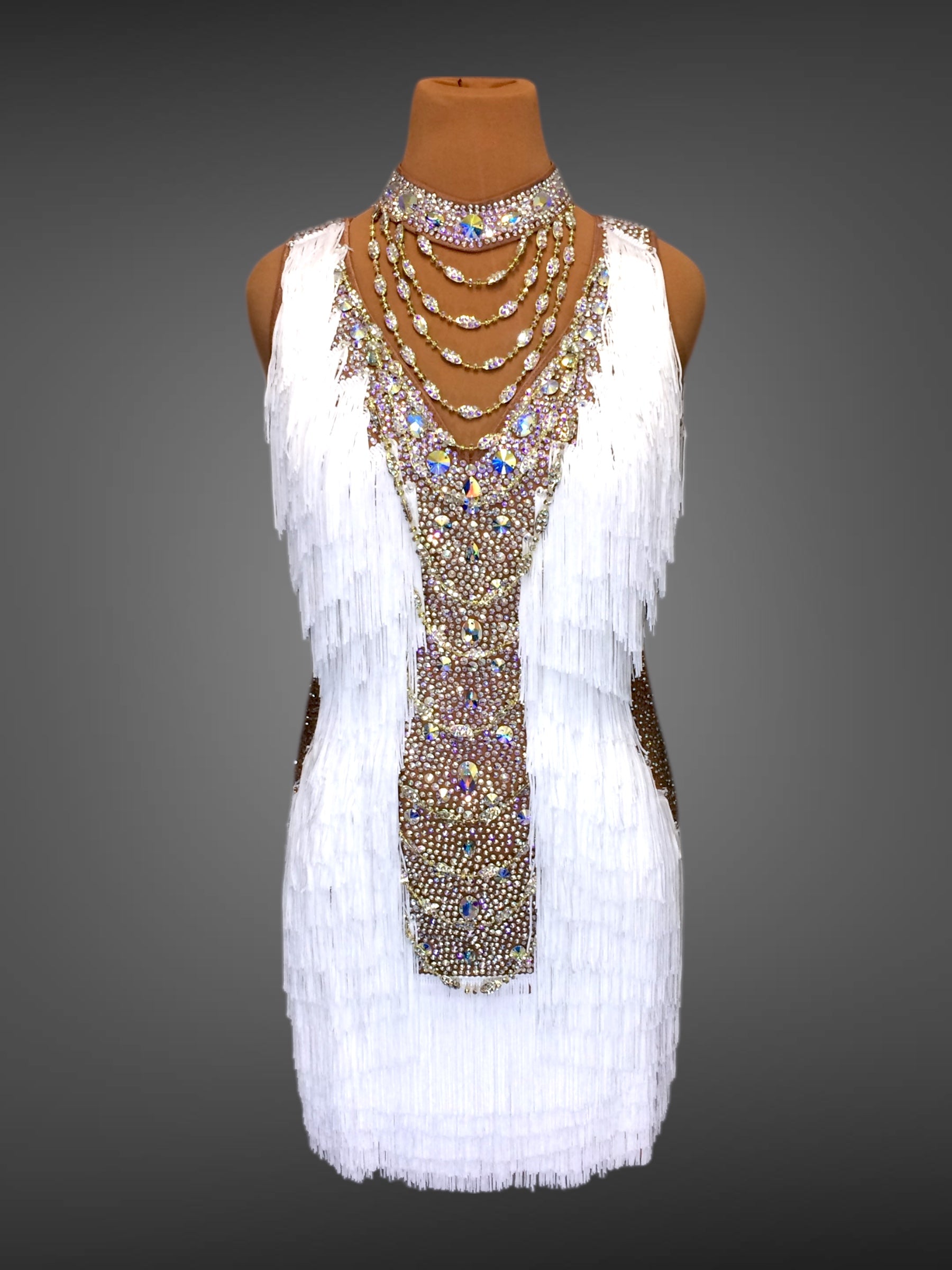 Mannequin wearing a white dress with beaded and fringed details on a gray background