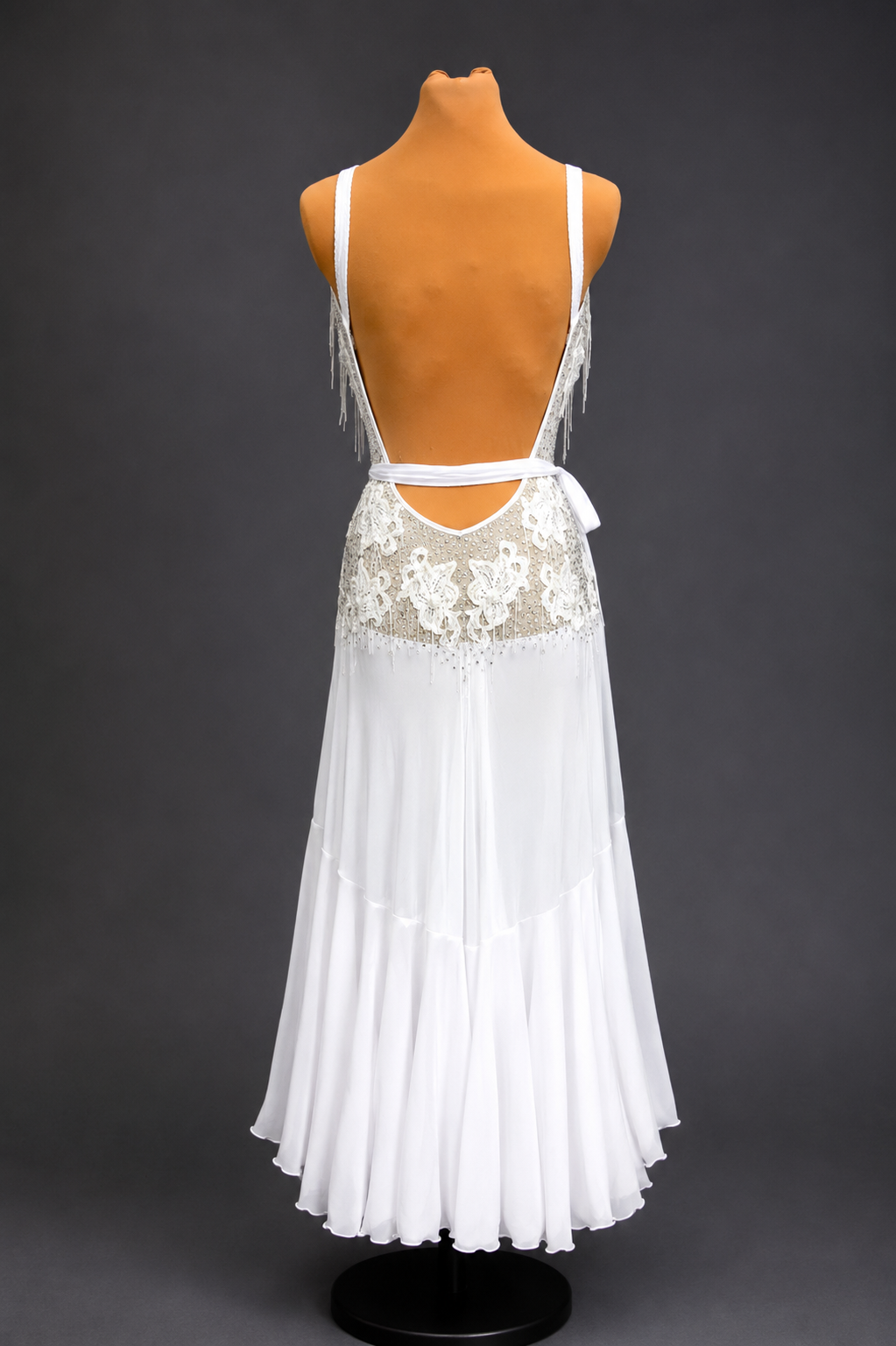 White dress with lace detailing on a mannequin against a dark background